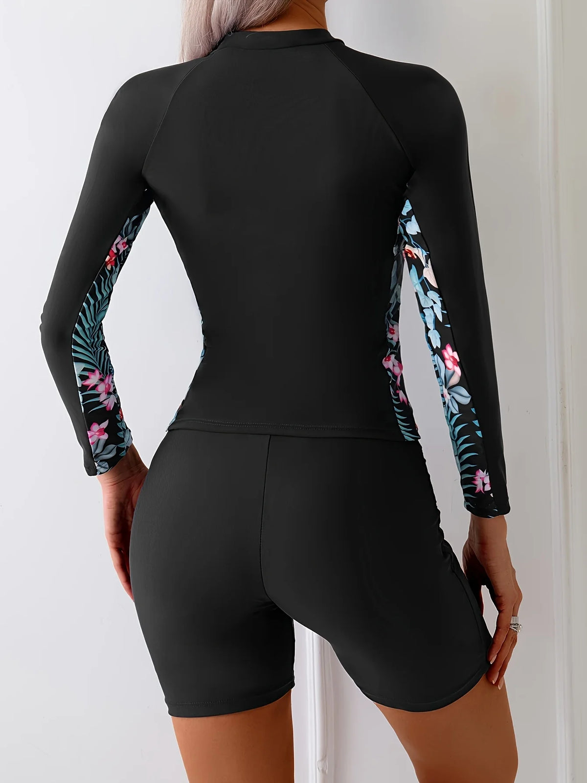 Long sleeve floral rashguard swimsuit showcasing black with floral side panels and boyleg style.